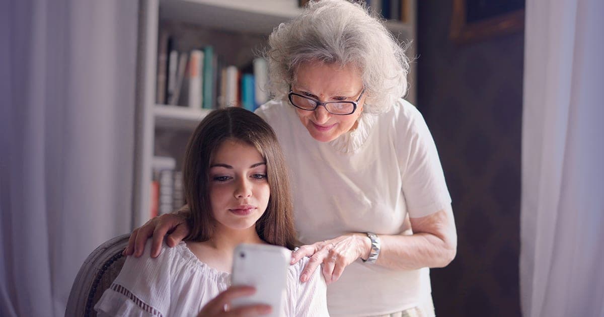 A senior being shown a smartphone by a family member — TELUS senior phone plans set up in store at Bolt Wireless